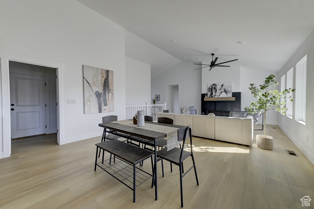 Dining space featuring high vaulted ceiling, ceiling fan, and light hardwood / wood-style flooring