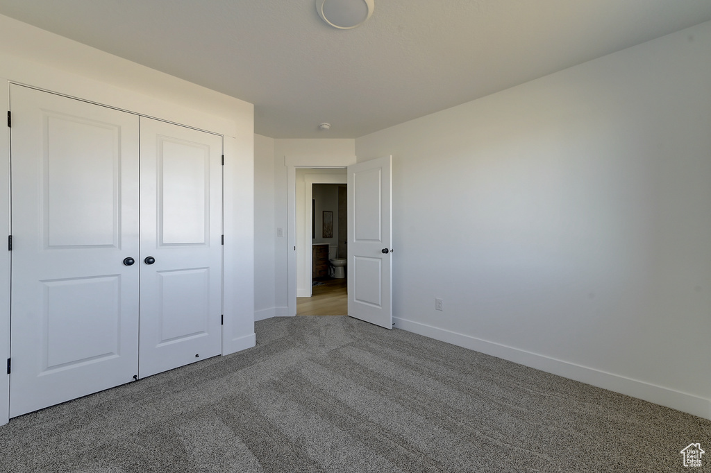 Unfurnished bedroom featuring light carpet and a closet