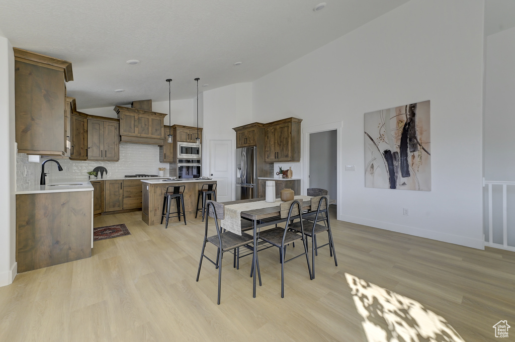 Dining room featuring light wood-type flooring, high vaulted ceiling, and sink