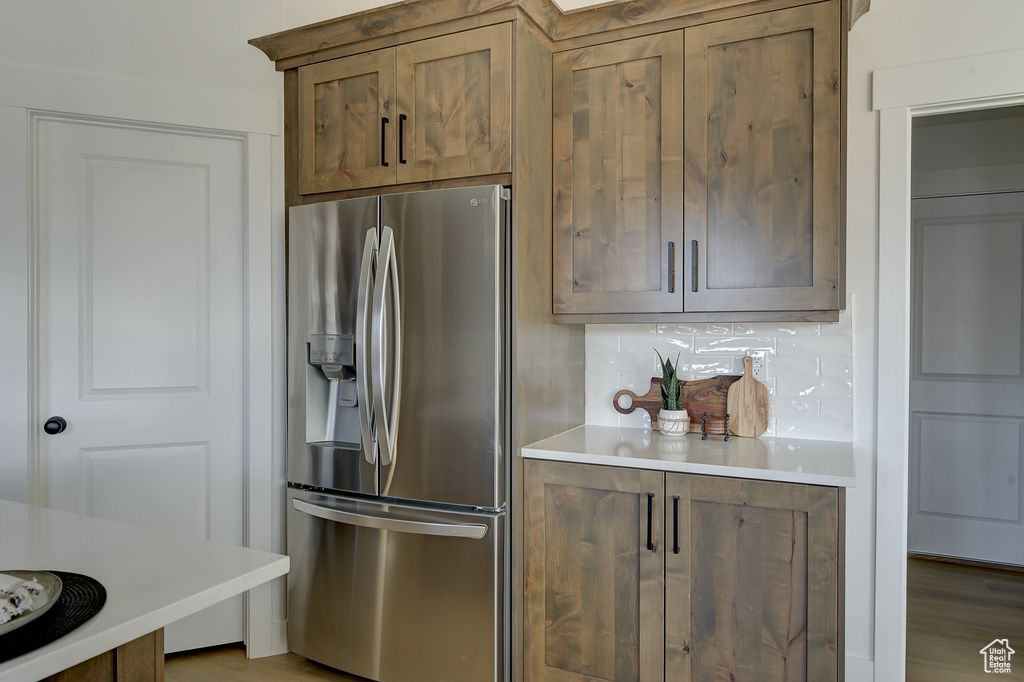 Kitchen with tasteful backsplash, stainless steel fridge, and light wood-type flooring