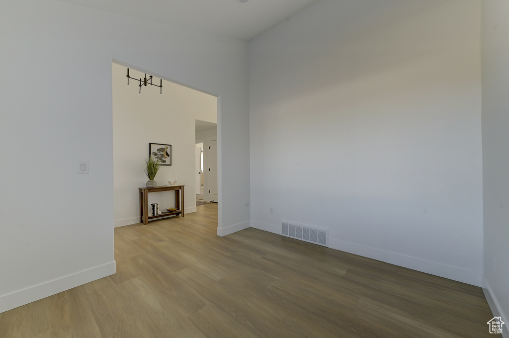 Spare room featuring a towering ceiling and wood-type flooring