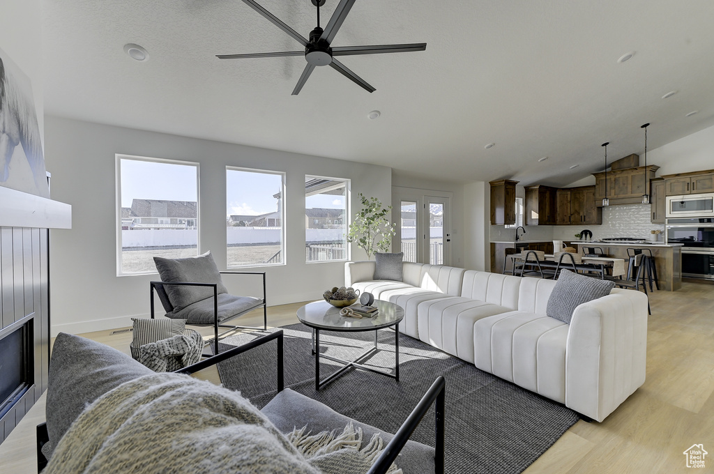 Living room with a healthy amount of sunlight, lofted ceiling, and light hardwood / wood-style floors