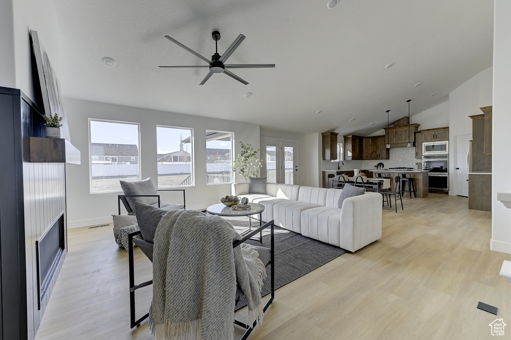 Living room with light hardwood / wood-style flooring, french doors, ceiling fan, vaulted ceiling, and sink