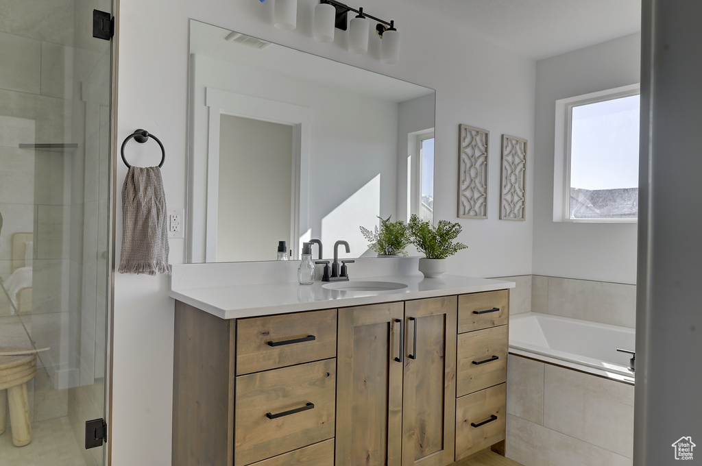 Bathroom featuring separate shower and tub and vanity