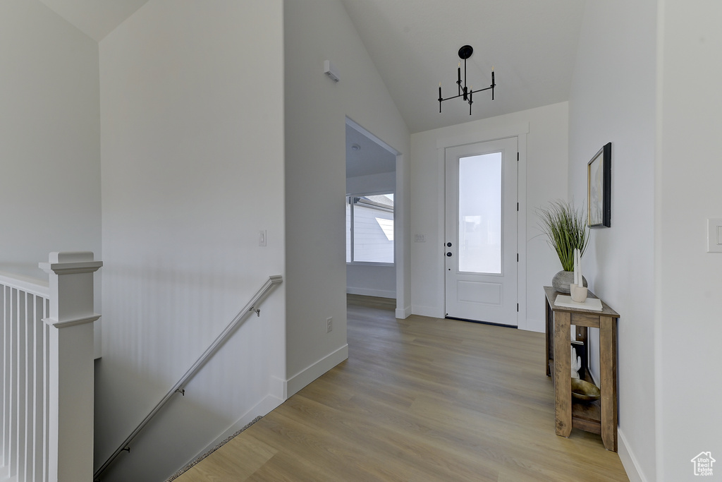 Foyer featuring light hardwood / wood-style floors, lofted ceiling, and a chandelier