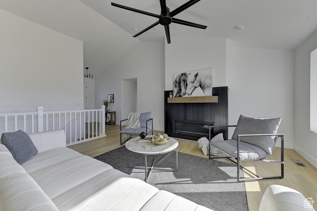 Living room featuring light wood-type flooring, high vaulted ceiling, and ceiling fan