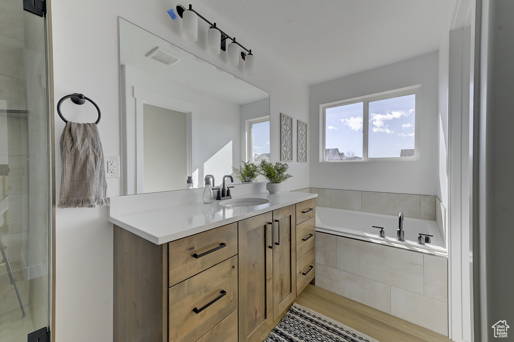 Bathroom featuring separate shower and tub and vanity