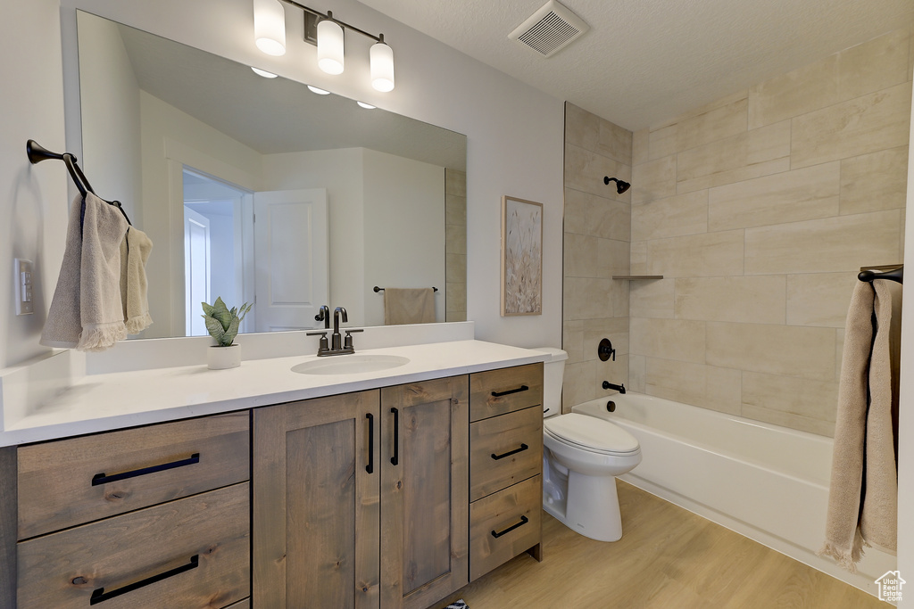 Full bathroom featuring toilet, vanity, tiled shower / bath, and wood-type flooring