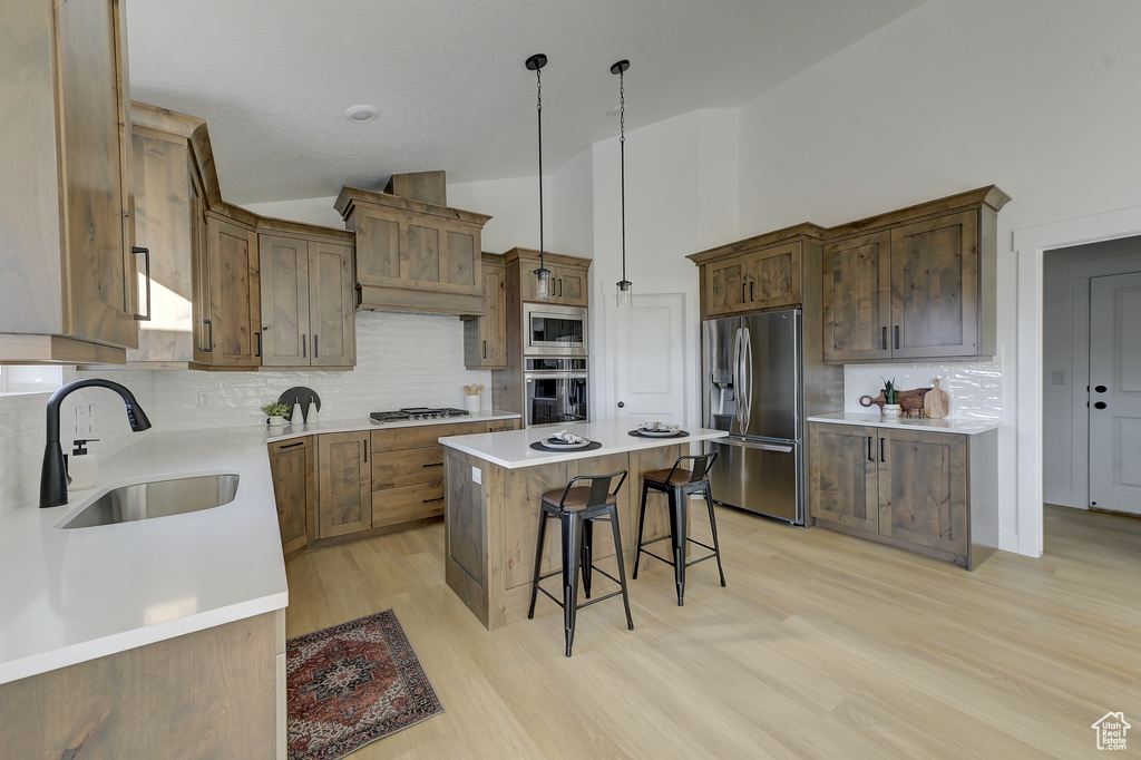 Kitchen featuring a center island, a breakfast bar, decorative light fixtures, sink, and appliances with stainless steel finishes