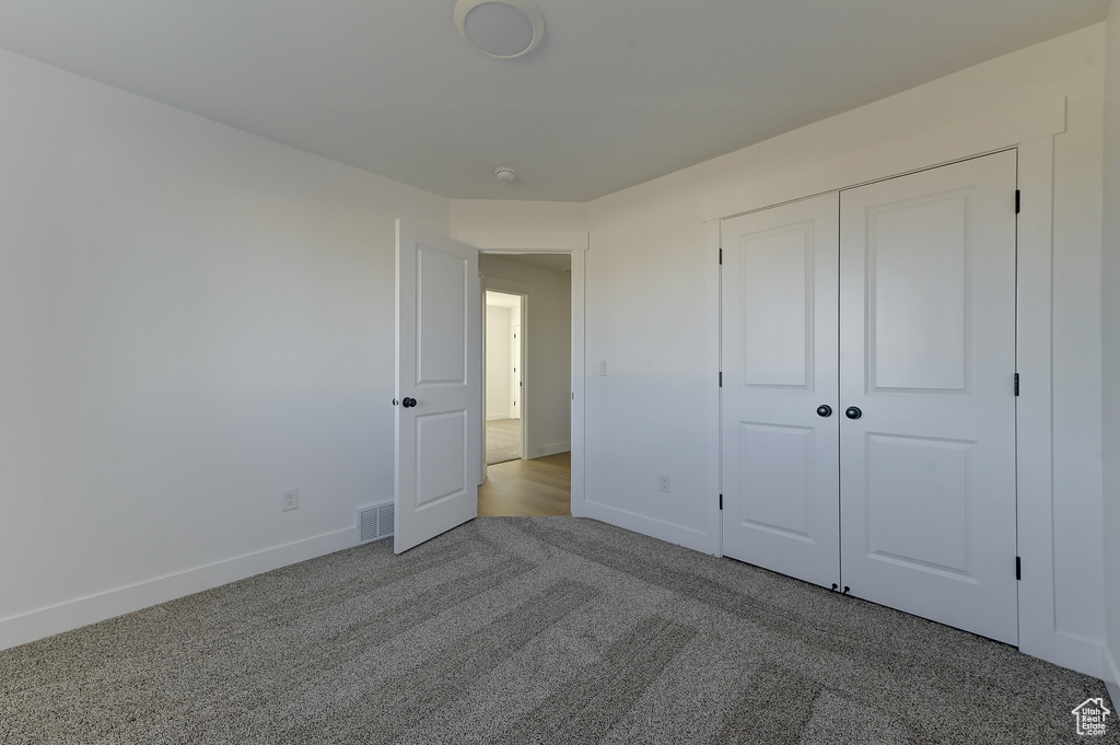 Unfurnished bedroom featuring a closet and light colored carpet