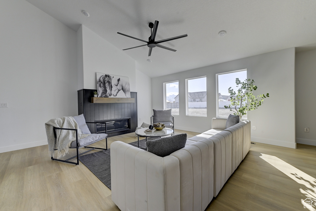 Living room with ceiling fan, light hardwood / wood-style flooring, and vaulted ceiling