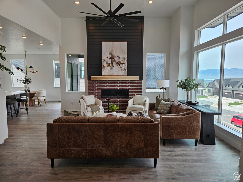 Living room with a high ceiling, ceiling fan, wood finished floors, a brick fireplace, and recessed lighting