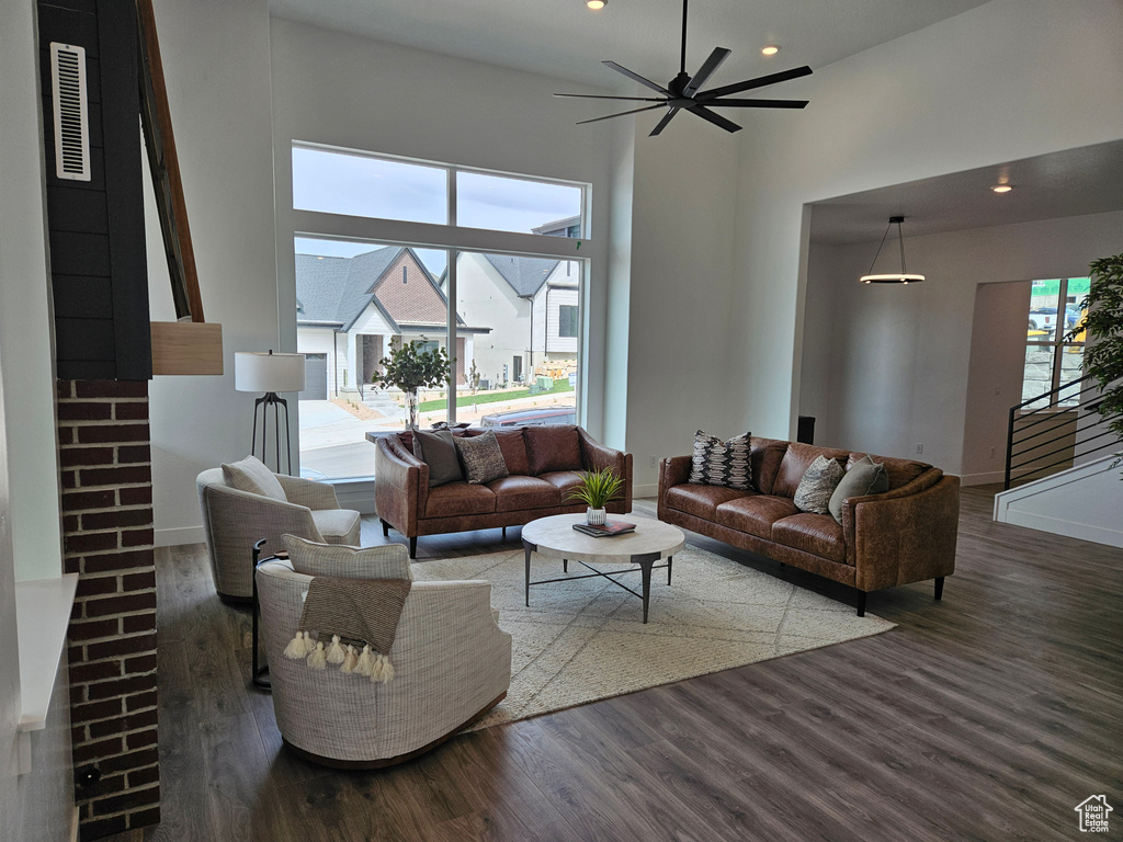 Living room with wood finished floors, a high ceiling, recessed lighting, baseboards, and a ceiling fan