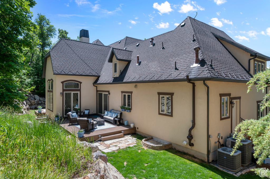 Rear view of house with an outdoor hangout area, stucco siding, a wooden deck, a chimney, and a lawn