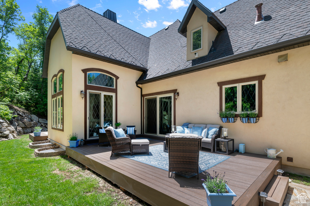 Back of property featuring an outdoor hangout area, stucco siding, a deck, and a yard