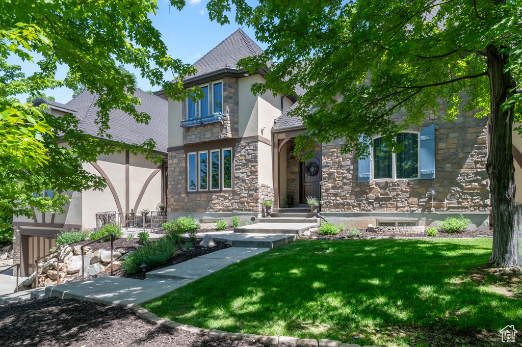 View of front of property with stone siding, stucco siding, and a front lawn