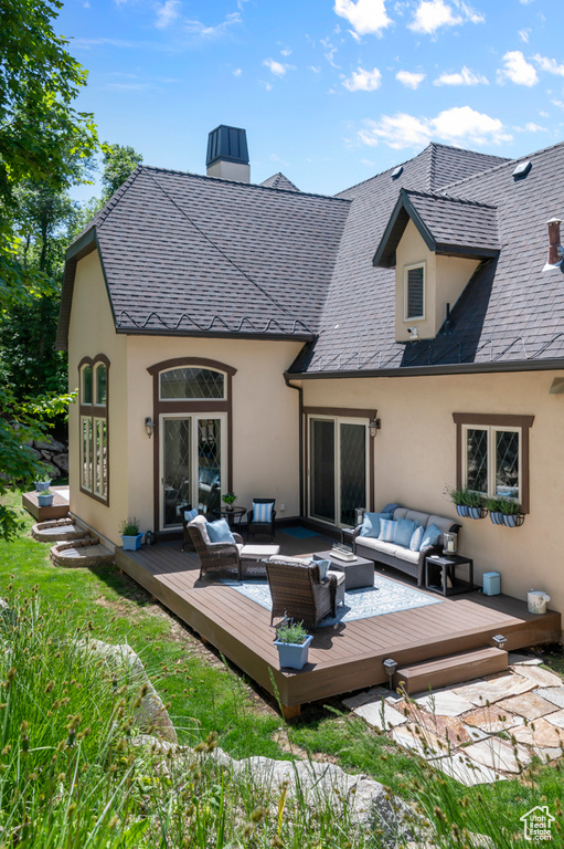 Rear view of property featuring an outdoor hangout area, stucco siding, a wooden deck, and a chimney
