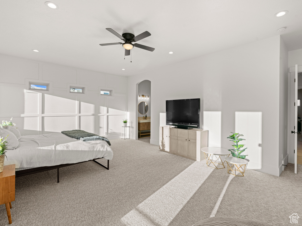 Carpeted bedroom featuring ensuite bathroom and ceiling fan