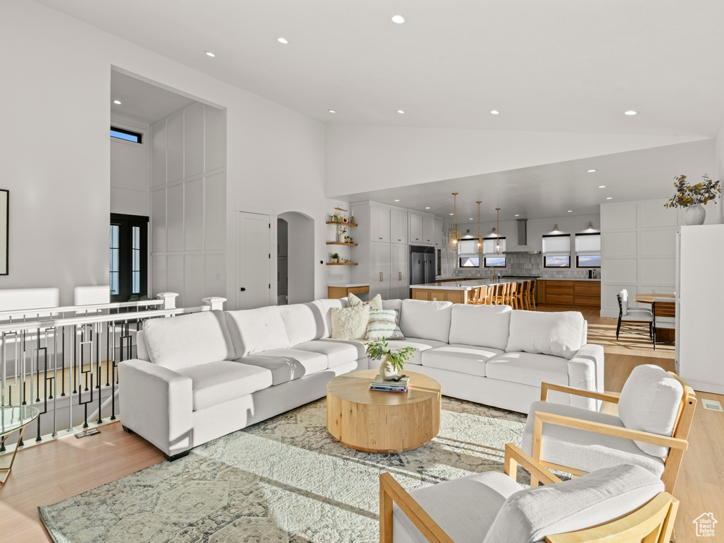 Living room featuring high vaulted ceiling and light hardwood / wood-style flooring