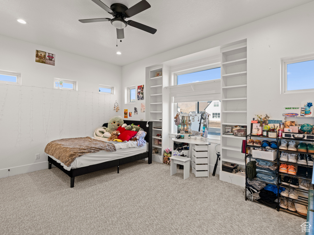 Carpeted bedroom featuring ceiling fan and multiple windows