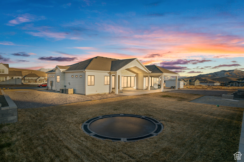 View of front of home with a yard, a mountain view, a patio area, and a trampoline