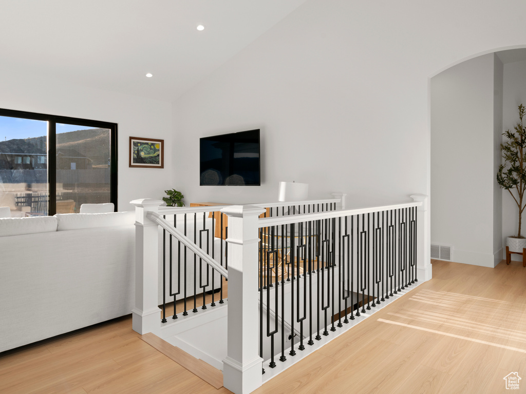 Stairway with vaulted ceiling and hardwood / wood-style floors