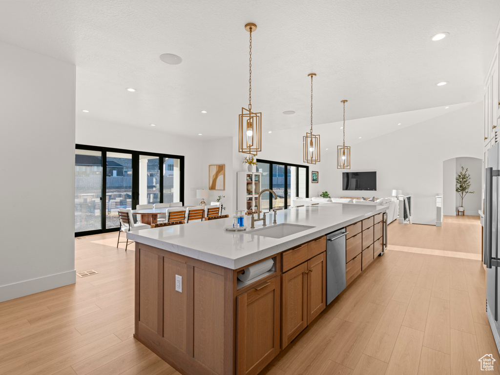 Kitchen featuring sink, dishwasher, hanging light fixtures, a spacious island, and vaulted ceiling