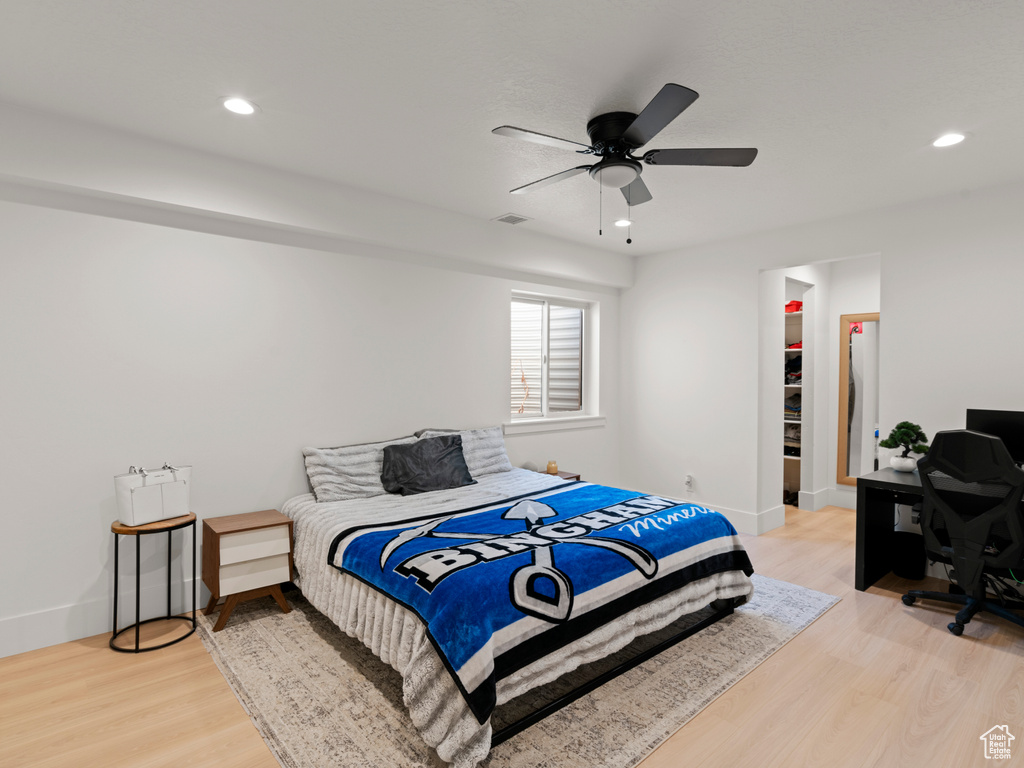 Bedroom with a spacious closet, light hardwood / wood-style floors, a closet, and ceiling fan