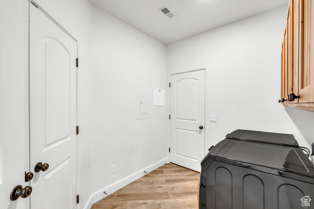 Washroom with cabinets, light hardwood / wood-style flooring, and washing machine and dryer