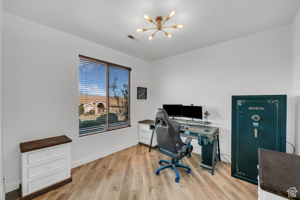 Office with light wood-type flooring and a chandelier