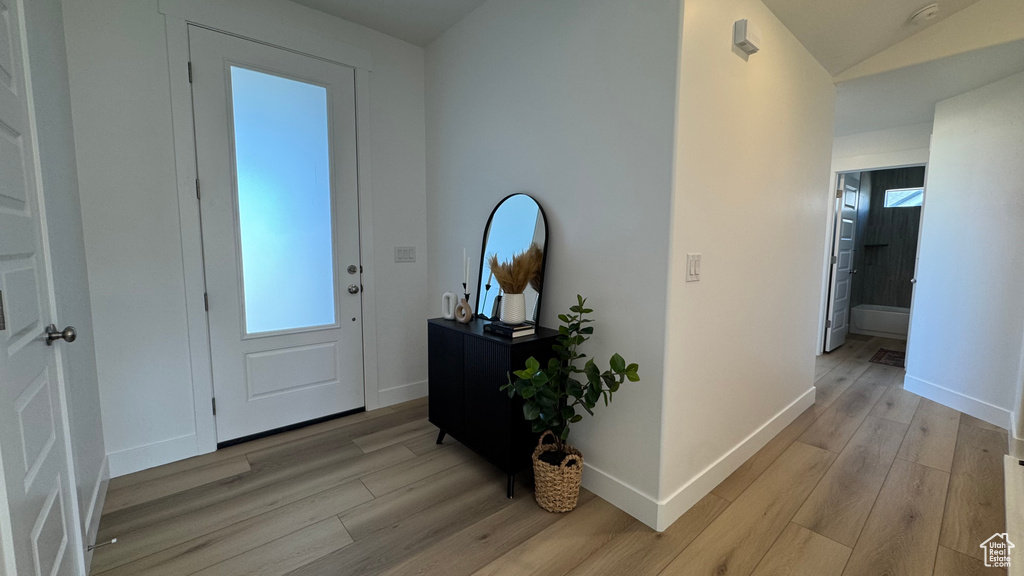 Entrance foyer with light wood-type flooring, baseboards, and vaulted ceiling