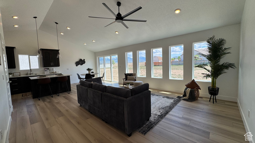 Living room with light wood-style floors, recessed lighting, a ceiling fan, baseboards, and high vaulted ceiling