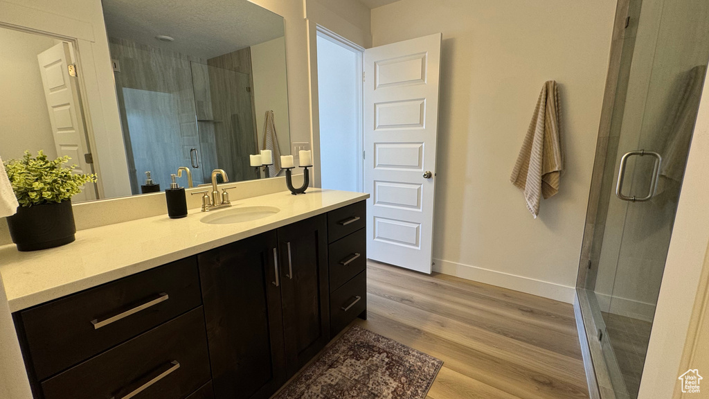 Full bathroom with a stall shower, wood finished floors, vanity, and baseboards