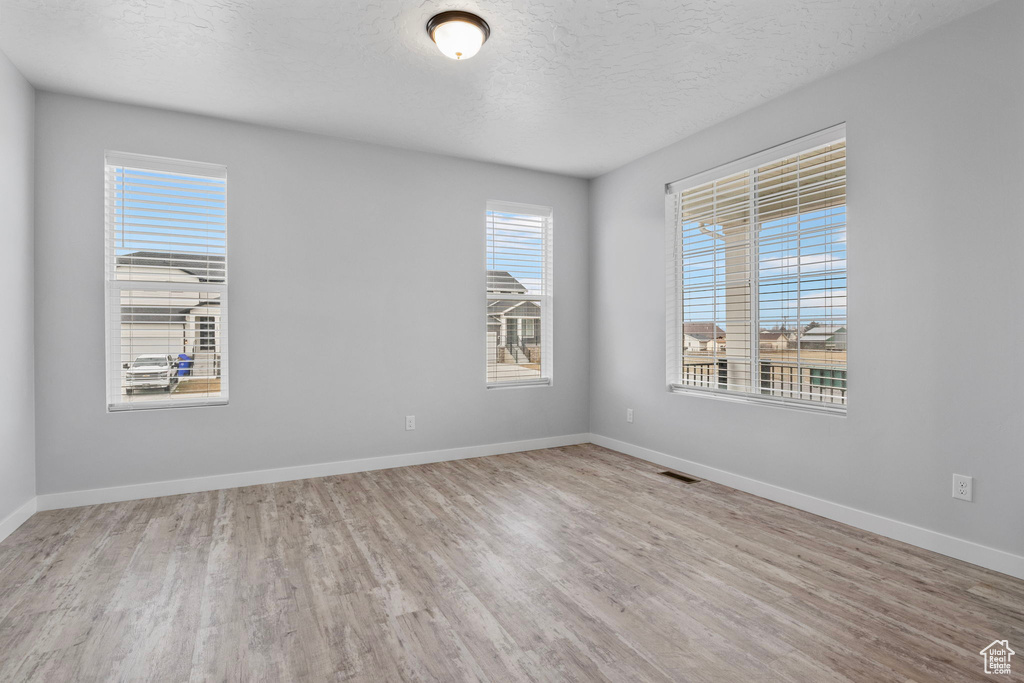 Empty room featuring light hardwood / wood-style flooring and a textured ceiling