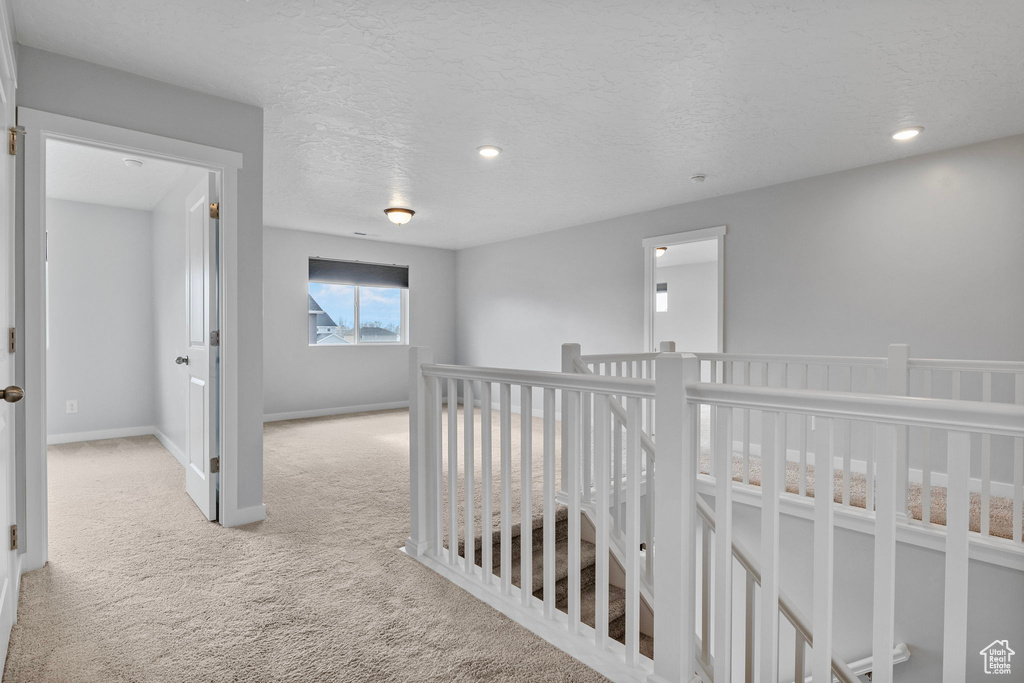 Hallway featuring light carpet and a textured ceiling