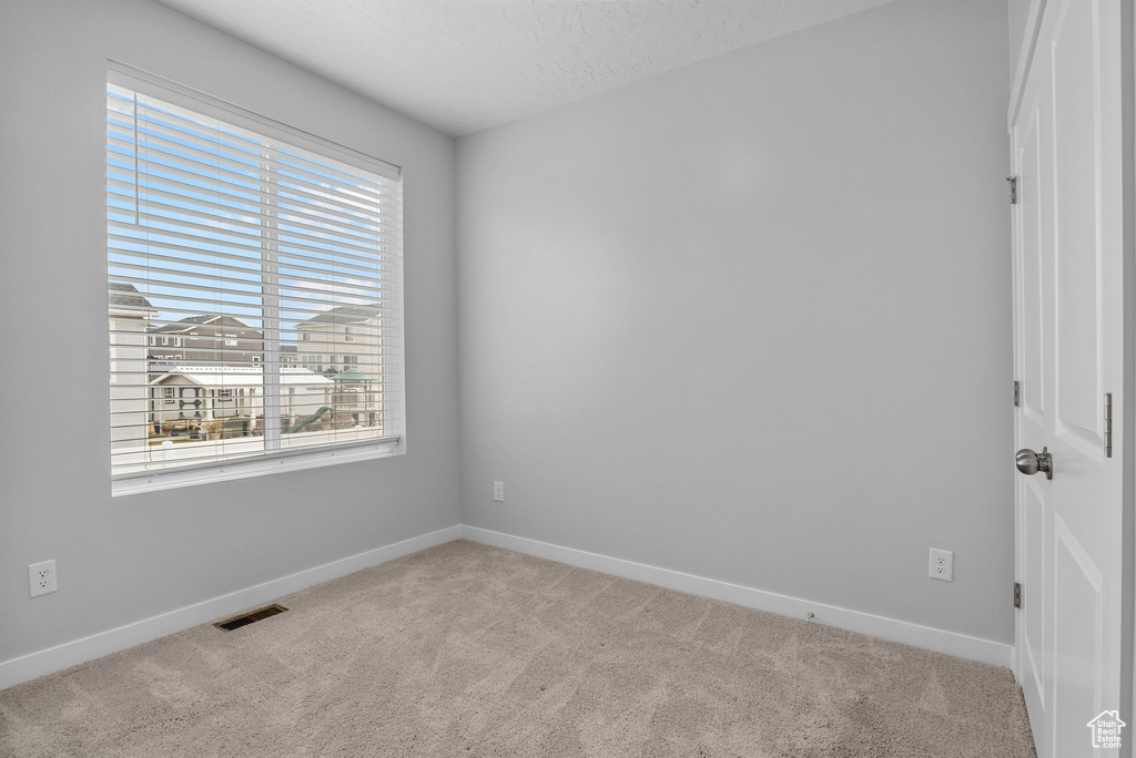 Empty room featuring light carpet and a textured ceiling