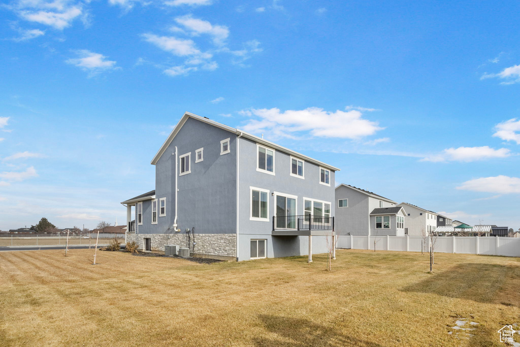 Rear view of house with cooling unit and a lawn