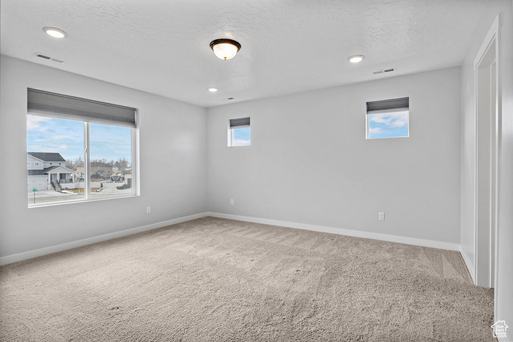 Carpeted spare room featuring plenty of natural light and a textured ceiling