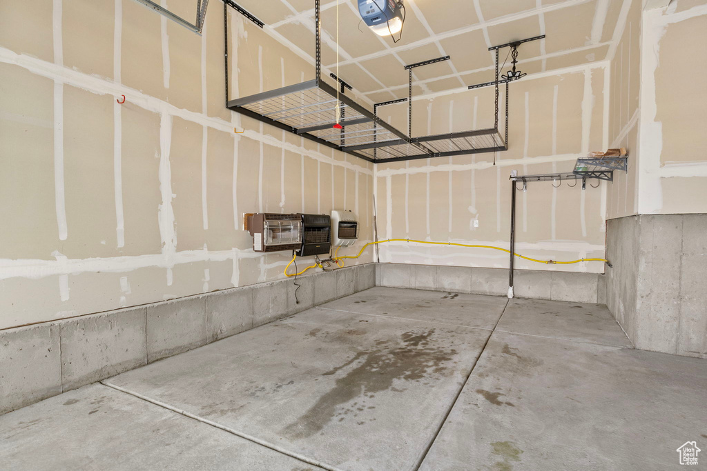 Garage featuring heating unit, a garage door opener, and a wall unit AC