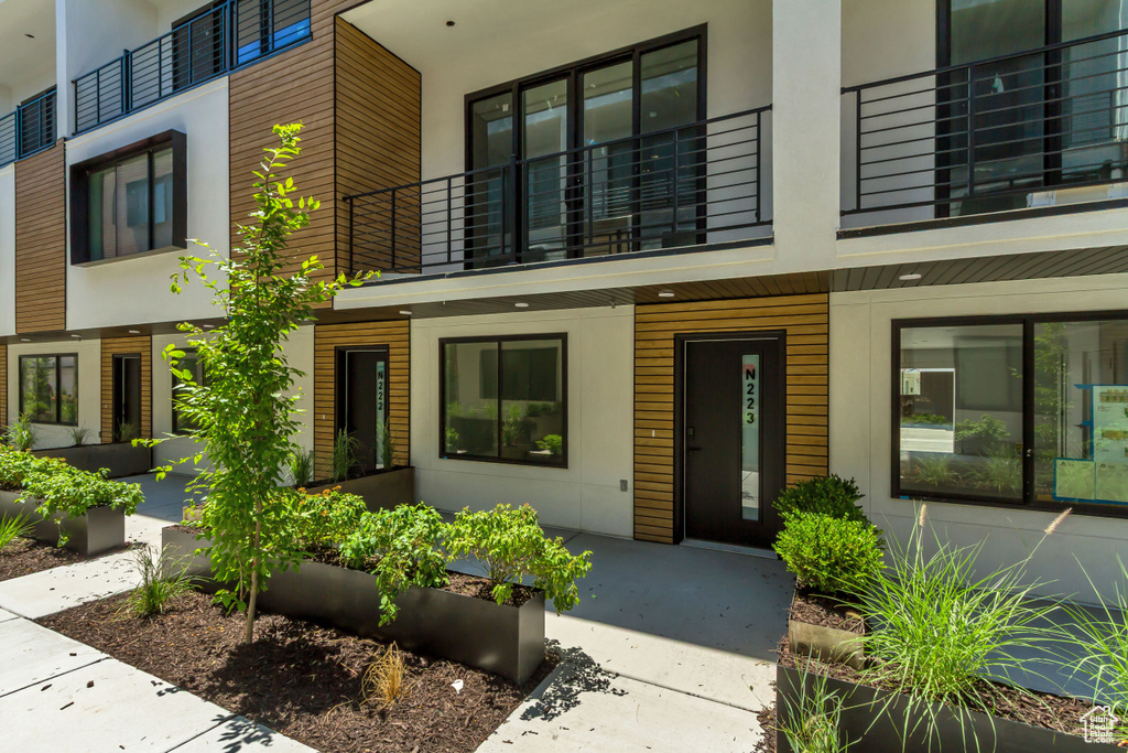 Property entrance with a balcony, stucco siding, and covered porch
