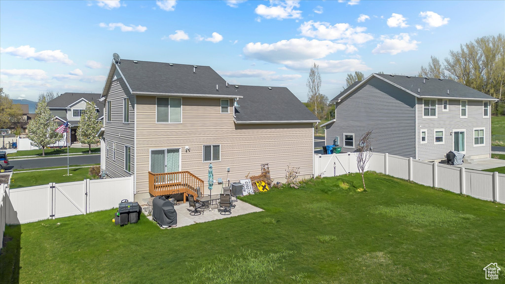 Back of property featuring a fenced backyard, a gate, a lawn, and a patio area