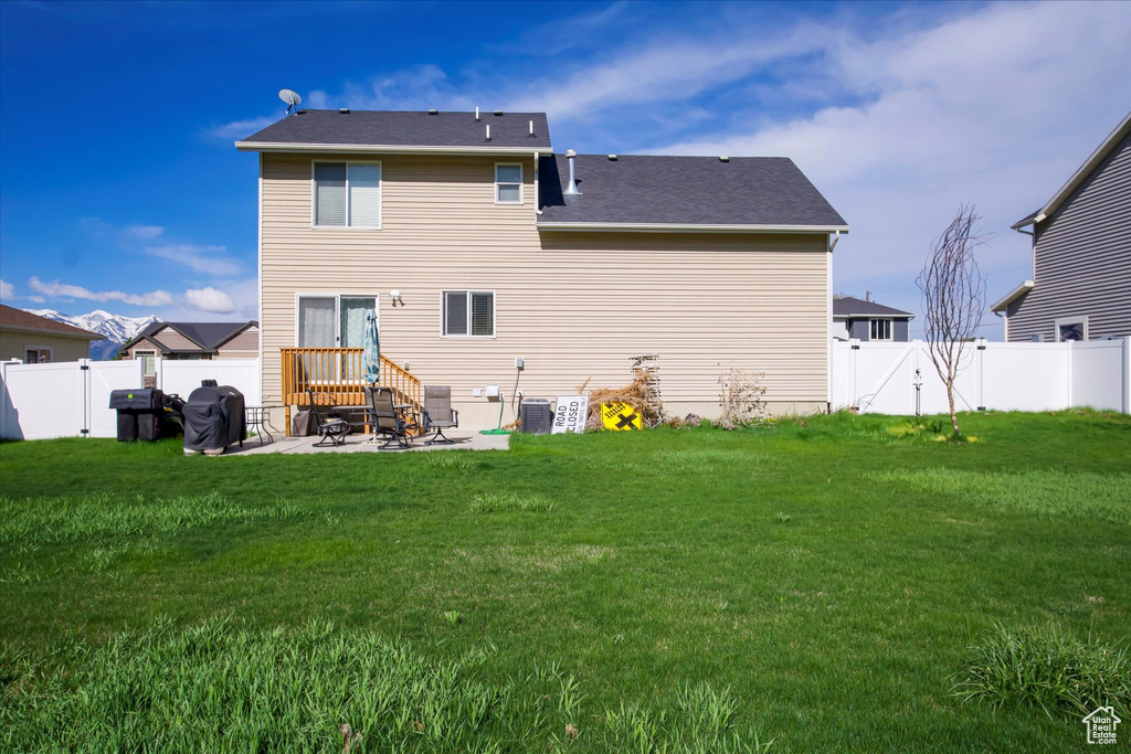 Rear view of property featuring a fenced backyard, a gate, a patio, and a yard
