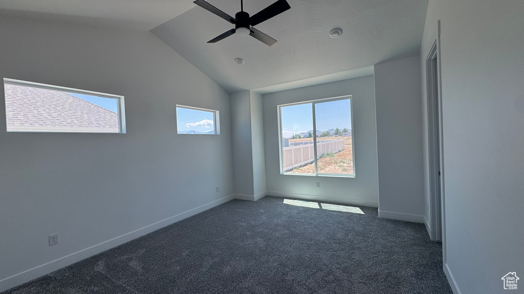 Carpeted spare room with a ceiling fan, lofted ceiling, and baseboards