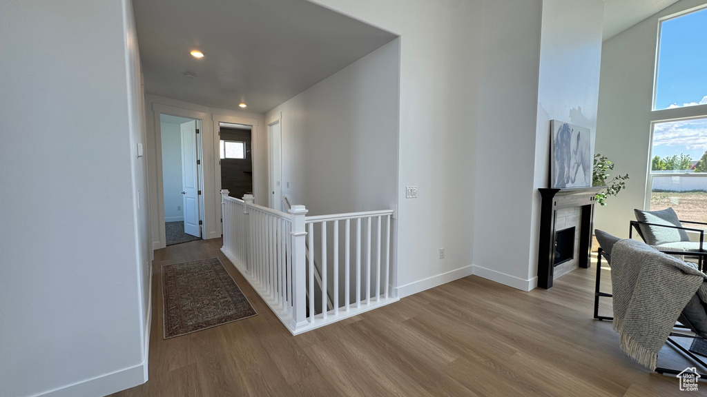 Corridor featuring an upstairs landing, wood finished floors, baseboards, recessed lighting, and a high ceiling