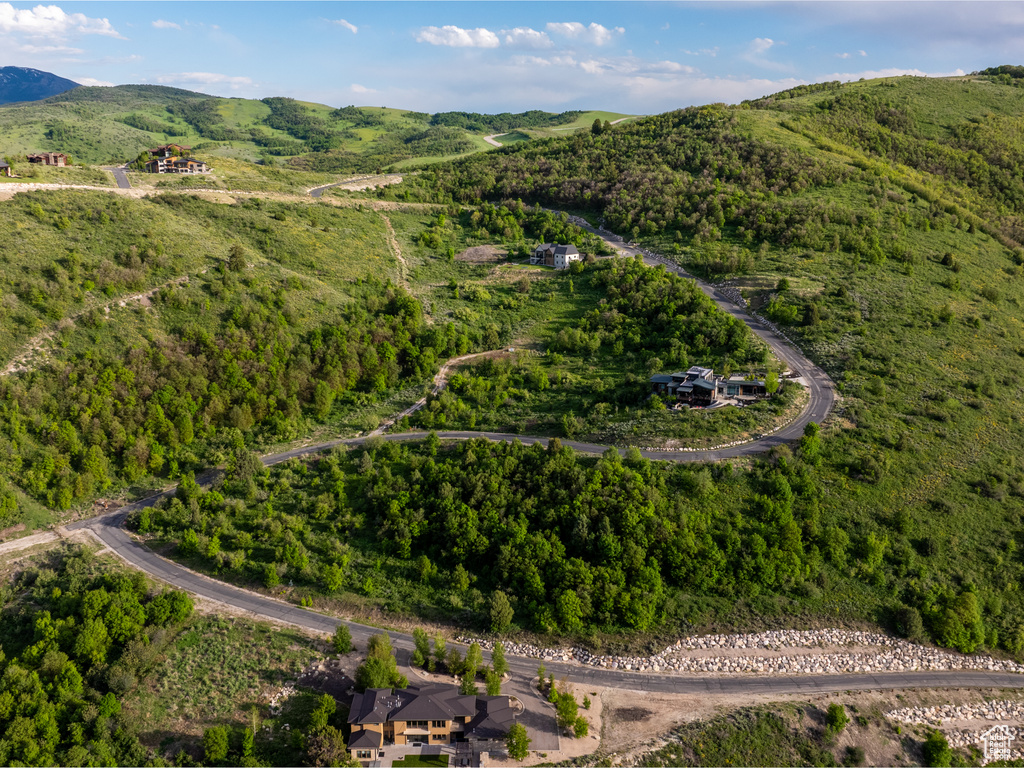 Aerial view of property and surrounding area with a forest and a mountain backdrop