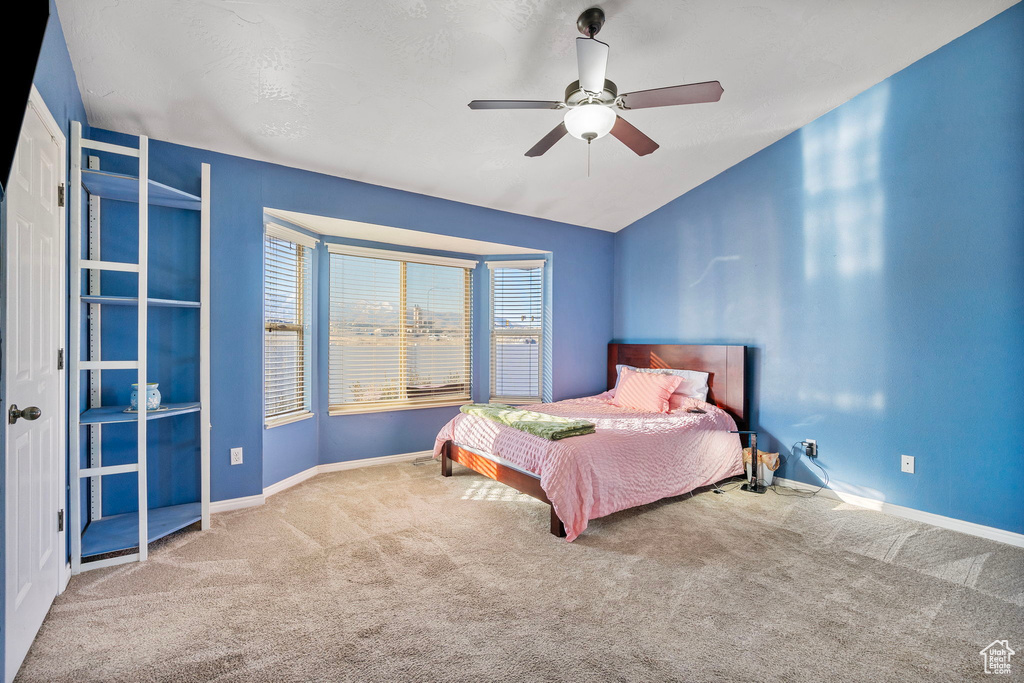 Bedroom with lofted ceiling, ceiling fan, and carpet flooring