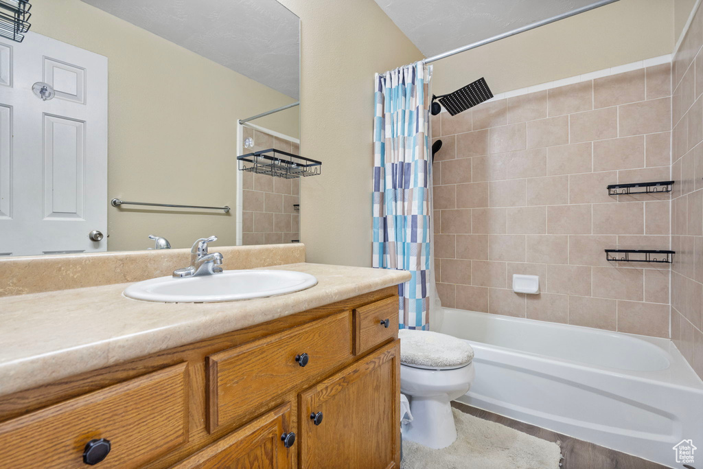 Full bathroom featuring vanity, shower / bath combination with curtain, and toilet