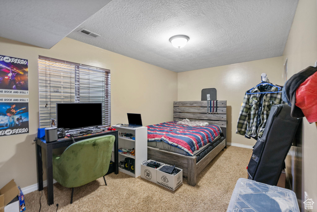 Bedroom featuring light colored carpet and a textured ceiling