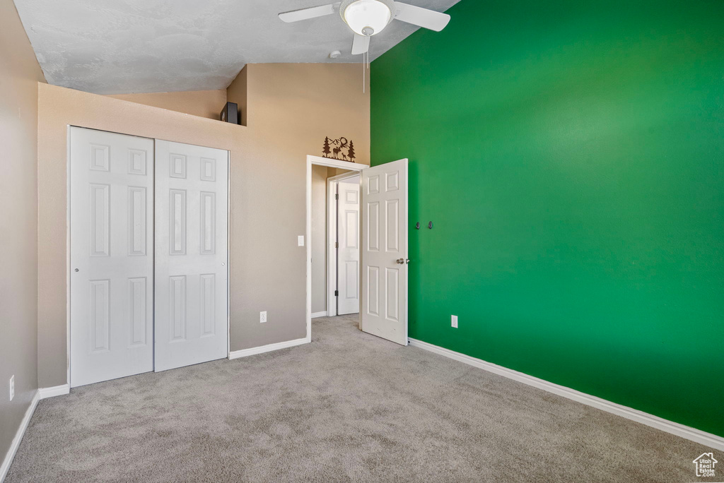 Unfurnished bedroom with ceiling fan, high vaulted ceiling, a textured ceiling, light carpet, and a closet