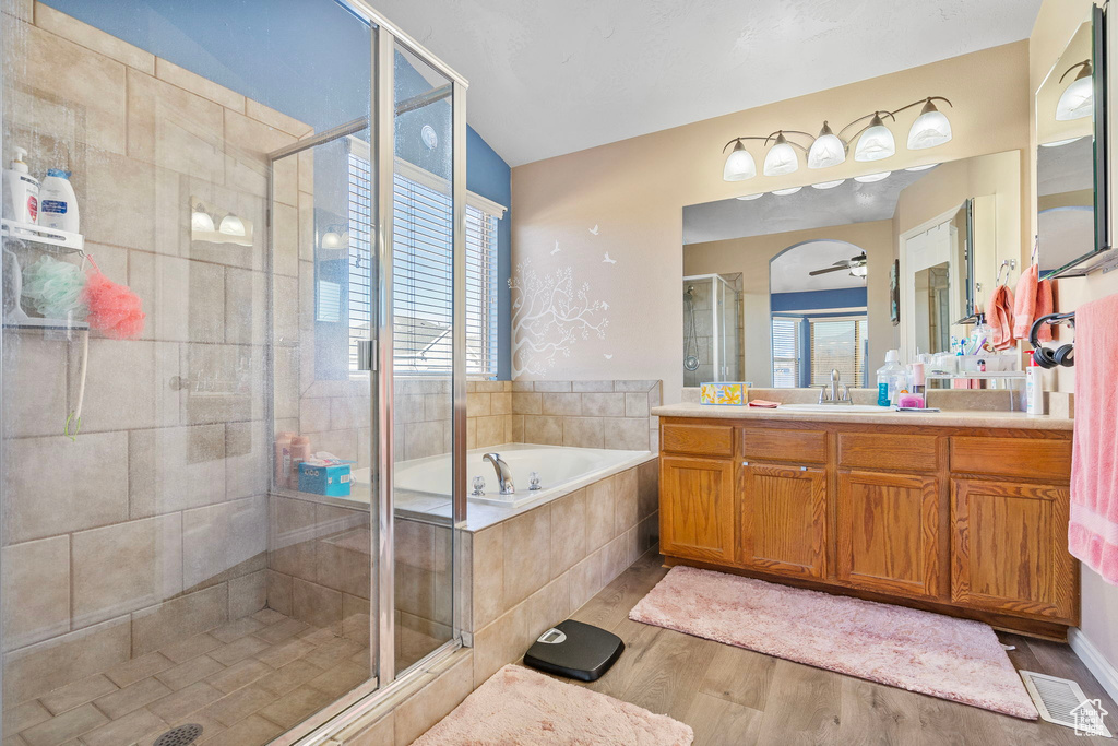 Bathroom with shower with separate bathtub, vaulted ceiling, vanity, hardwood / wood-style flooring, and ceiling fan